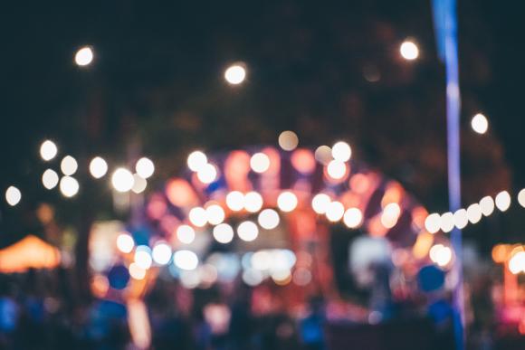 A blurred image of a night scene with colorful lights and bokeh effect, depicting an outdoor event or festival
