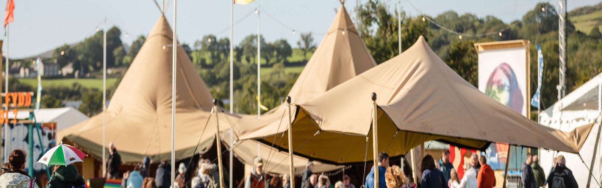 Teepees brown gyda baneri o'u hamgylch. Caffi Maes B