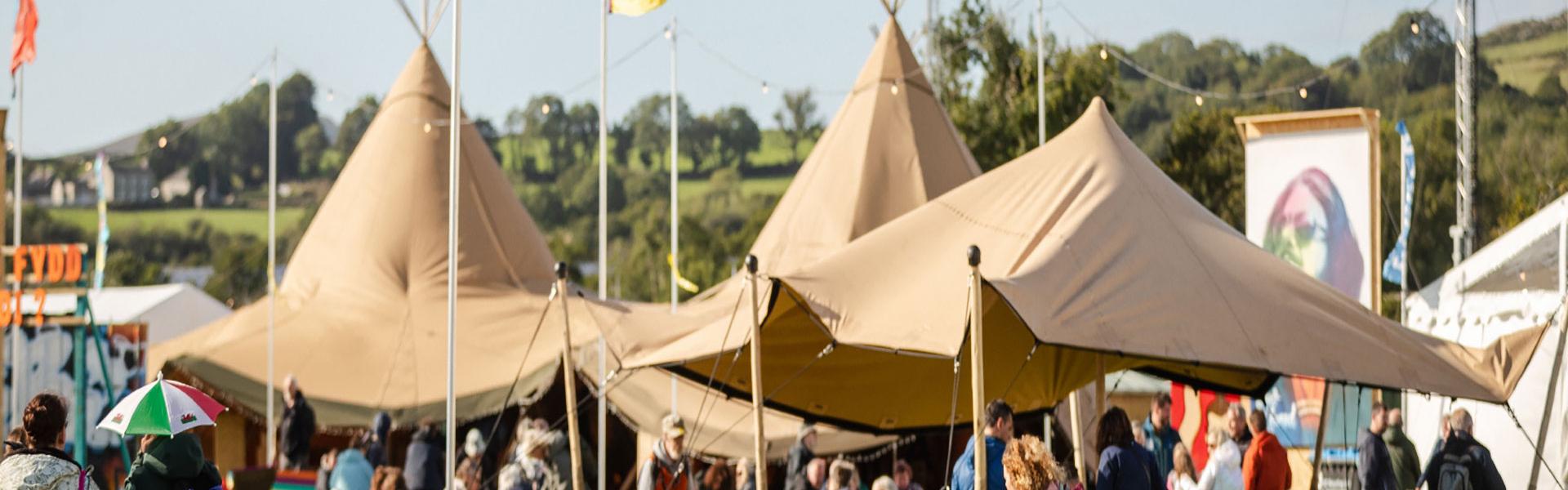 Teepees brown gyda baneri o'u hamgylch. Caffi Maes B
